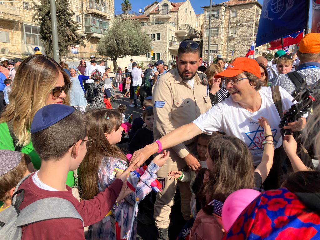 Hennie Keegstra deelt kaartjes uit aan een groepje kinderen langs de kant van de weg tijdens de Jeruzalem-mars 2022